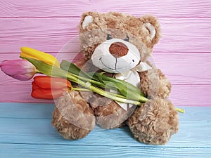 Bear softness teddy toy with tulips birthday childhood on a wooden