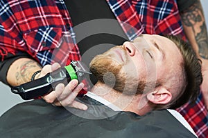 Beard care. man while trimming his facial hair cut at the barbershop