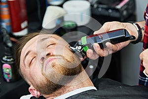 Beard care. man while trimming his facial hair cut at the barbershop