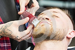 Beard care. man while trimming his facial hair cut at the barbershop