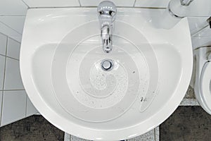 beard hair and stubble in wash sink in bathroom after haircut and shave forgotten to clean