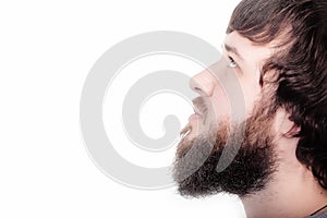 Beard is his style. Close-up profile of bearded man standing against white background without any emotions, just calm.