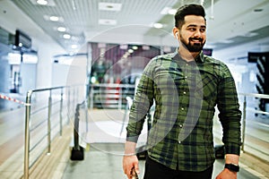 Beard indian guy with mobile phone pose at trade center against escalator