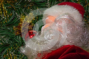 Beard Santa Clause decoration toy is under Christmas tree. Close up image with soft focus