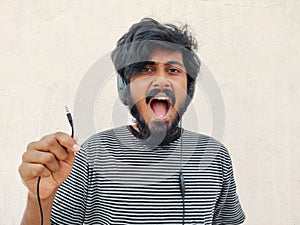 with beard shouting and showing his headphones are unplugged