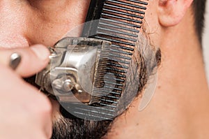 Beard trimming with an old beard shaving machine. Bearded man shaving his beard