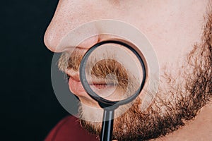 Beard under a magnifying glass. hairline on a man`s face close up. portrait of a guy with a mustache