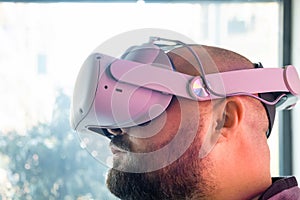 Bearded adult man in virtual reality headset looking up. Overweight male gamer in VR glasses. Modern technology for work