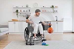 Bearded adult with mobility impairment dribbling ball in studio apartment.