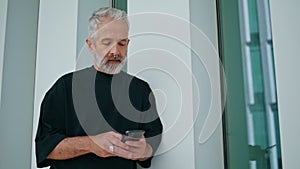 Bearded adult texting mobile phone on street. Focused grey hair senior using