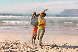 Bearded african american senior man dancing with happy mature woman against sea and sky in summer