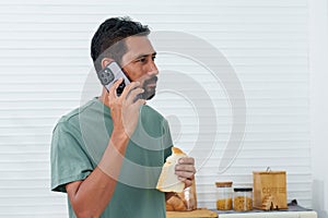Bearded Asian man wearing comfortable pajamas clothes on holiday morning, waking up phone call from someone who misses, stand