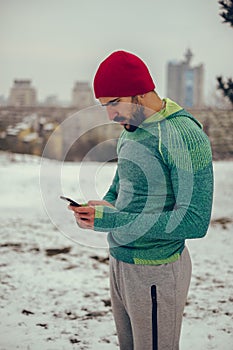 Bearded athlete using mobile phone outdoor