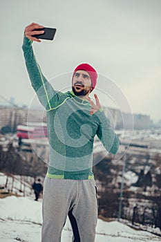 Bearded athletic man taking selfie with cityscape in the background