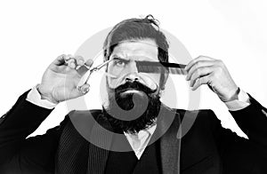 Bearded barber man in barbershop. Scissors and straight razor. Vintage style beard and mustache.