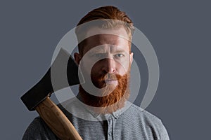 bearded barber man with sharp axe blade has red beard. studio shot of bearded barber man.