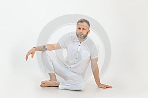 Bearded barefoot thoughtful man with tattoo sitting on the floor. Small business, yoga and pilates sports studio coach