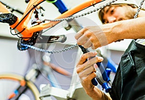 Bearded bicycle mechanic doing his professional work in workshop - Young trendy man checking bike chain inside superbikes