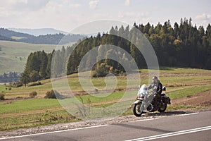 Bearded biker with long hair in black leather jacket sitting on modern motorcycle.