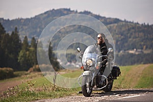 Bearded biker with long hair in black leather jacket sitting on modern motorcycle.