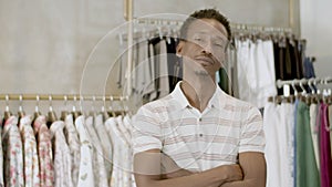 Bearded black man standing with folded arms in clothing store.
