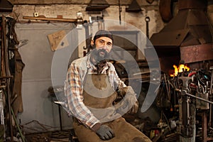 Bearded blacksmith after working in his workshop. Blacksmith`s workshop.