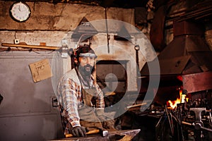 Bearded blacksmith after working in his workshop. Blacksmith& x27;s workshop.