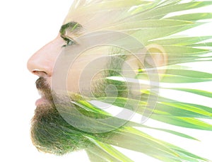 A bearded bold man profile double exposure portrait close up combined with a photo green tropical foliage