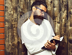 Bearded brutal caucasian doctor or postgraduate student with notebook