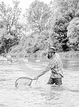 Bearded brutal fisher catching trout fish with net. If fish regularly you know how rewarding and soothing fishing is