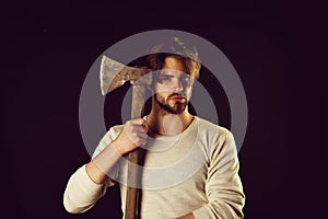Bearded brutal guy with casual hairstyle holds old sharp axe