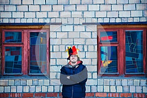 Bearded brutal man in the hat of a buffoon stands near the brick wall