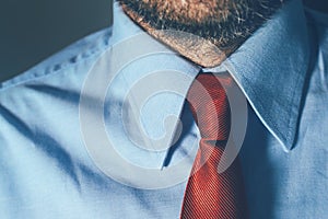 Bearded businessman in blue shirt and red necktie