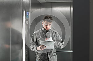 Bearded businessman is concentrated while reading the documents in the lift. Portrait of a diligent male office worker checking