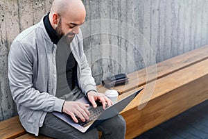 Bearded businessman freelancer working on laptop outdoors. Man typing on laptop keyboard. Remote work, online marketing