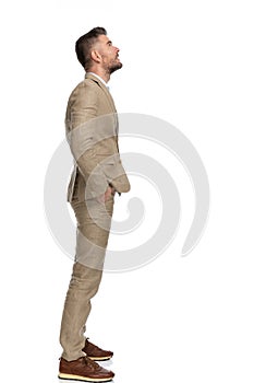 Bearded businessman with hands in pockets standing in line and looking up