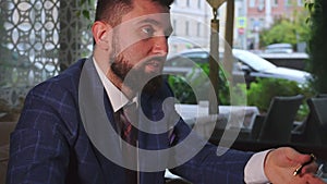 Bearded businessman in jacket holds conference in restaurant