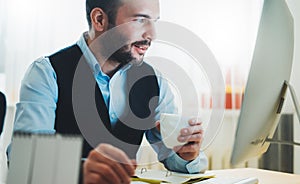 Bearded businessman looking in monitor computer at home workplace. man drinking coffee working at social distance,  consultant