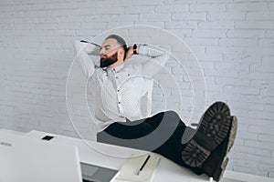 Bearded businessman sitting at desk in office and relaxation