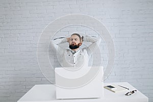 Bearded businessman sitting at desk in office and relaxation