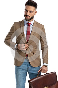 Bearded businessman with suitcase unbuttoning jacket