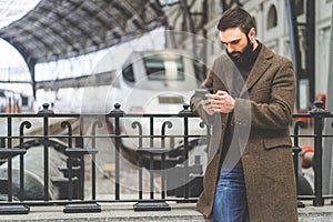 Bearded businessman texting sms message on his mobile phone.Casual professional entrepreneur using smartphone at hall of