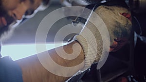 A bearded car mechanic twists the bolt into the motor housing.