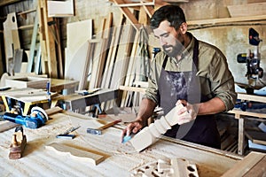 Bearded Carpenter Carving Stair Posts in Shop