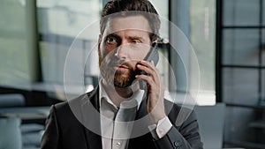 Bearded Caucasian middle-aged adult business man talking phone at office explain negotiate virtual sales conversation