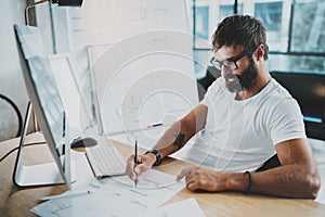 Bearded coworker professional wearing eye glasses working at modern loft studio-office with desktop computer.White blank