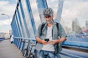 Bearded cyclist using phone while waiting for bus.