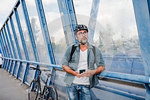 Bearded cyclist using phone while waiting for bus.