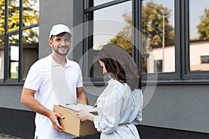 Bearded delivery man holding box near