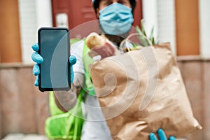 Bearded delivery man wearing mask and gloves due to the emergence of the Covid19 virus, showing smartphone, holding